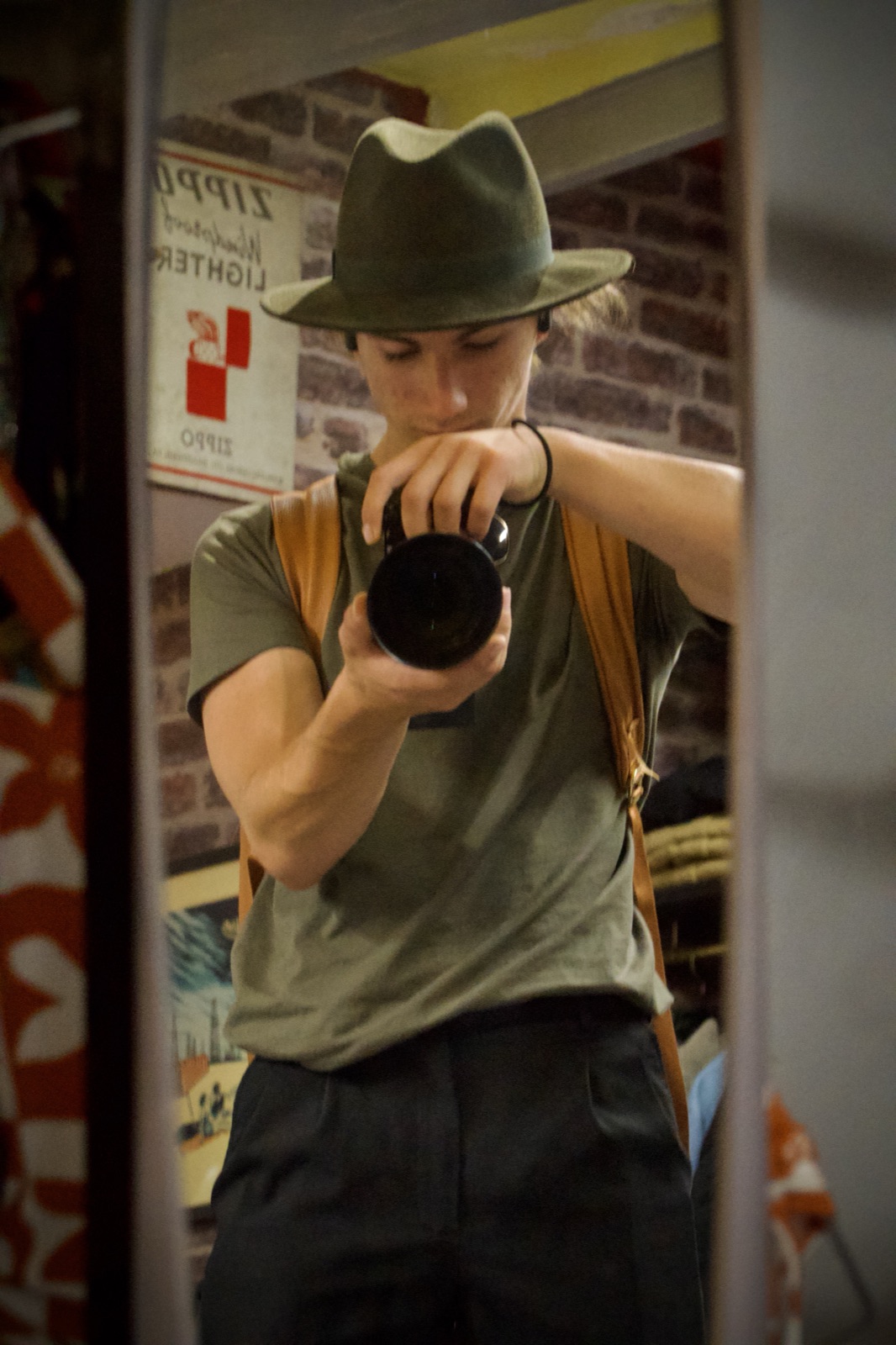 Flavio de face dans un miroir, chapeau vert sur la tête, un objectif photo à la main